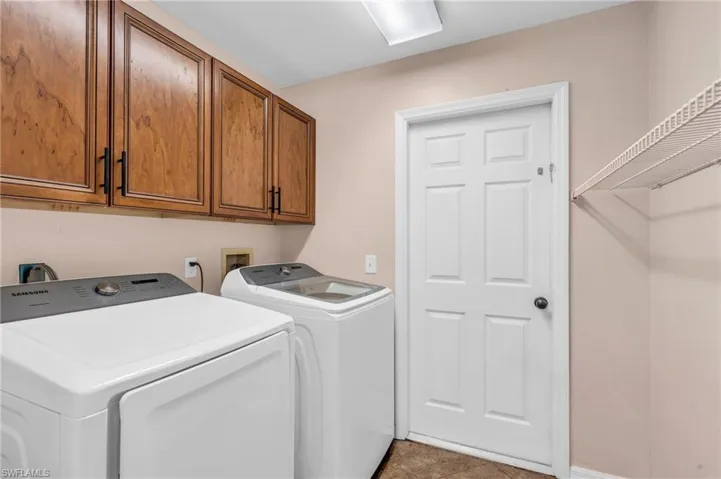 Washroom featuring washing machine and dryer, cabinets, and light tile patterned floors
