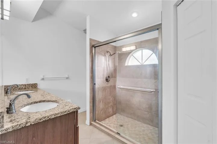 Bathroom featuring vanity, a shower with shower door, and tile patterned flooring