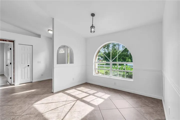Spare room featuring lofted ceiling and light tile patterned floors