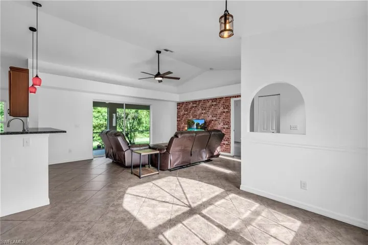 Living room with lofted ceiling, sink, ceiling fan, and tile patterned floors