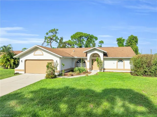 Ranch-style house featuring a garage and a front lawn