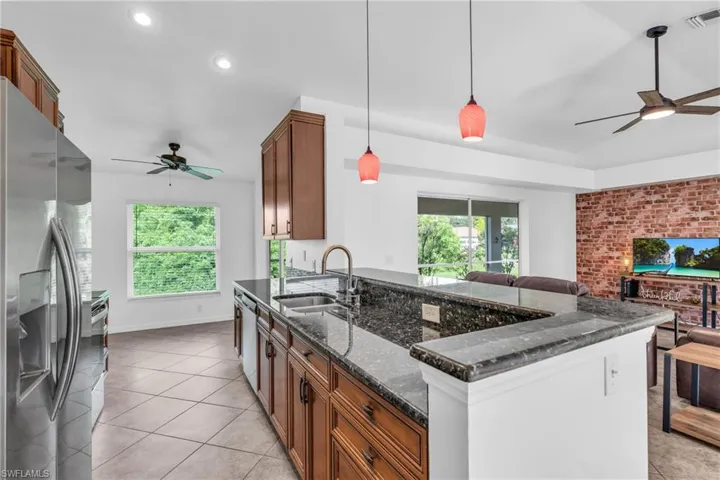 Kitchen featuring hanging light fixtures, ceiling fan, sink, and stainless steel refrigerator with ice dispenser