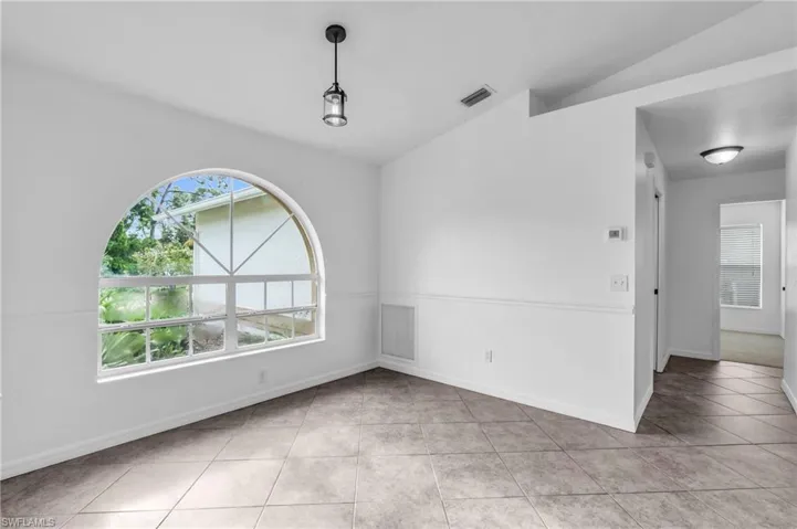Tiled spare room featuring vaulted ceiling