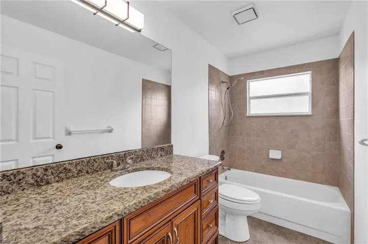 Full bathroom with tile patterned floors, tiled shower / bath, toilet, and vanity