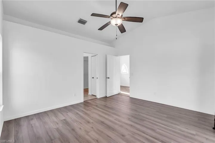 Spare room featuring vaulted ceiling, hardwood / wood-style flooring, and ceiling fan