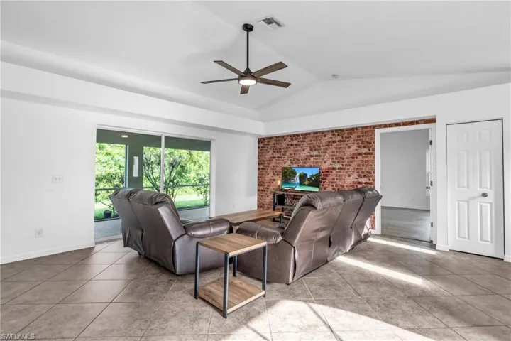 Tiled living room featuring a fireplace, lofted ceiling, and ceiling fan