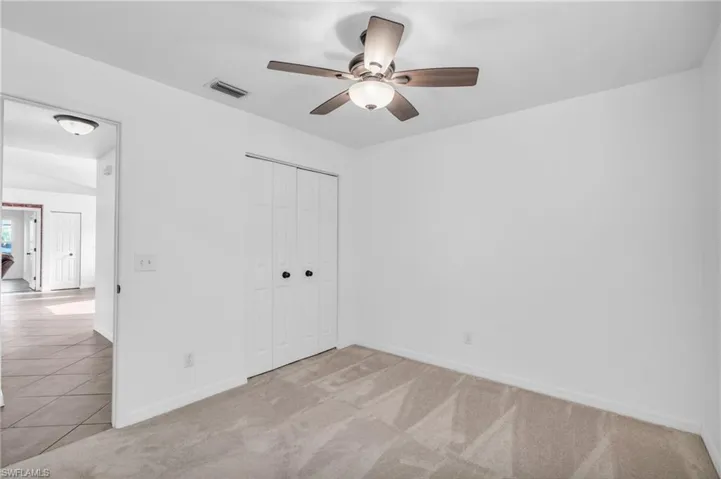 Unfurnished bedroom with vaulted ceiling, light colored carpet, ceiling fan, and a closet