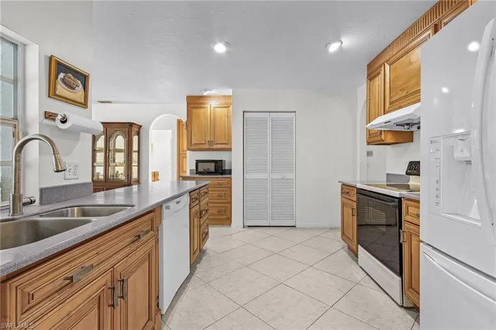 Kitchen with white appliances, sink, a textured ceiling, light tile patterned flooring, and extractor fan
