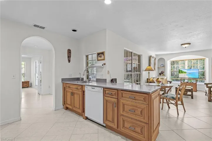 Kitchen with white dishwasher, sink, a textured ceiling, light tile patterned flooring, and kitchen peninsula