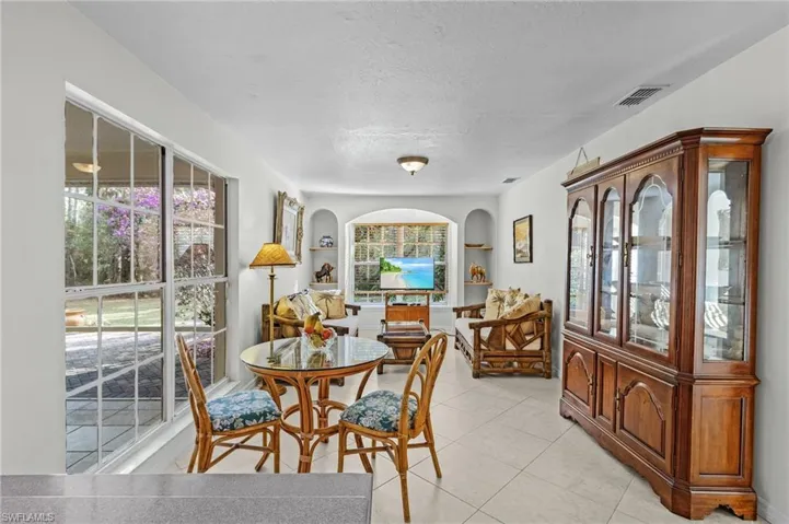 Family room with built in shelves, light tile patterned flooring, and a textured ceiling