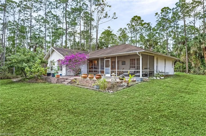 View of rear of home featuring a sunroom and a front lawn