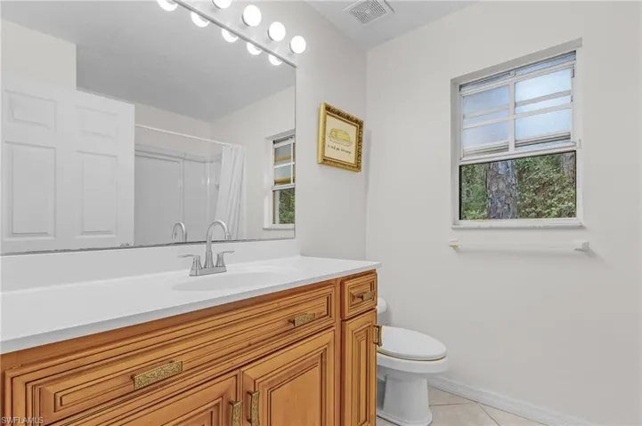 Bathroom with tile patterned flooring, vanity, toilet, and walk in shower