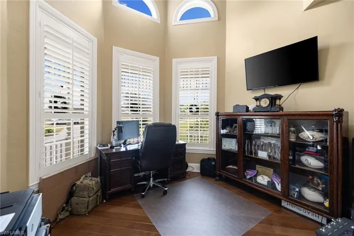 Home office featuring dark wood-style flooring and a high ceiling