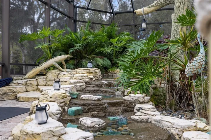 View of yard with glass enclosure, a sunroom, a patio, and a garden pond