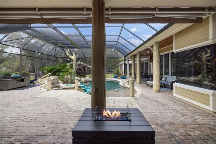 Swimming pool with a patio area, a sunroom, glass enclosure, and an outdoor fire pit