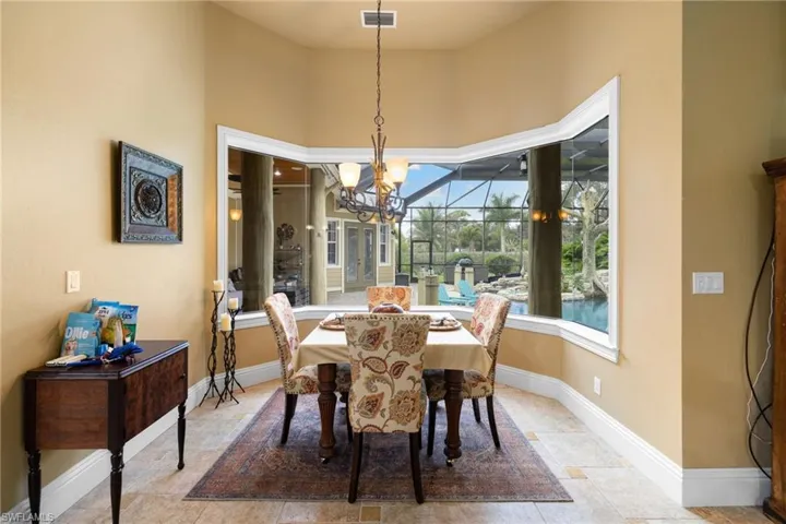 Dining area featuring suspended lighting, stone tile flooring, and a high ceiling