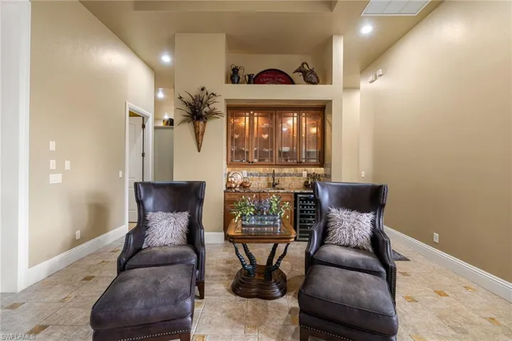 Sitting room with a high ceiling, wine cooler, bar area, and recessed lighting