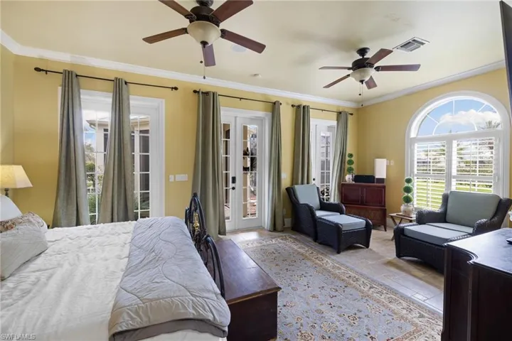 Bedroom featuring crown molding, stone tile floors, access to exterior, and ceiling fan