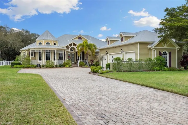 View of front of house with covered porch, a front yard, decorative driveway, and an attached garage