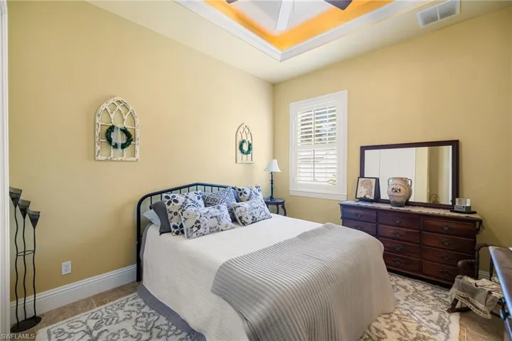 Bedroom with a raised ceiling and a ceiling fan
