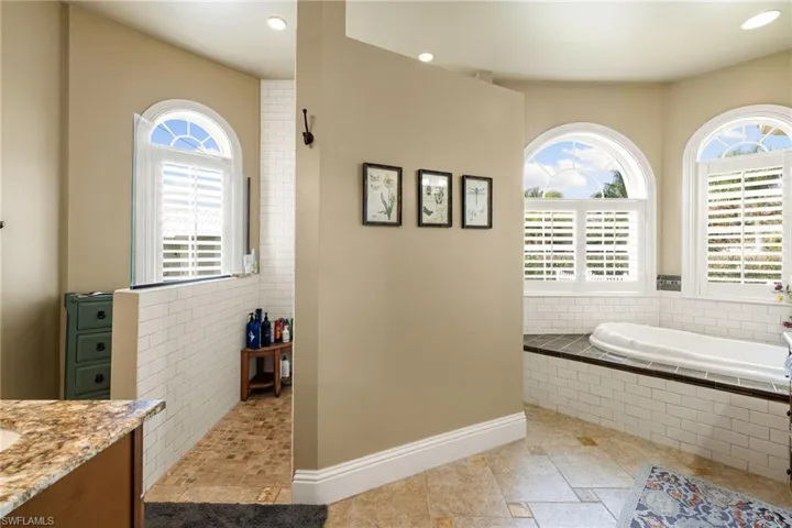 Full bathroom featuring healthy amount of natural light, vanity, a bath, and recessed lighting