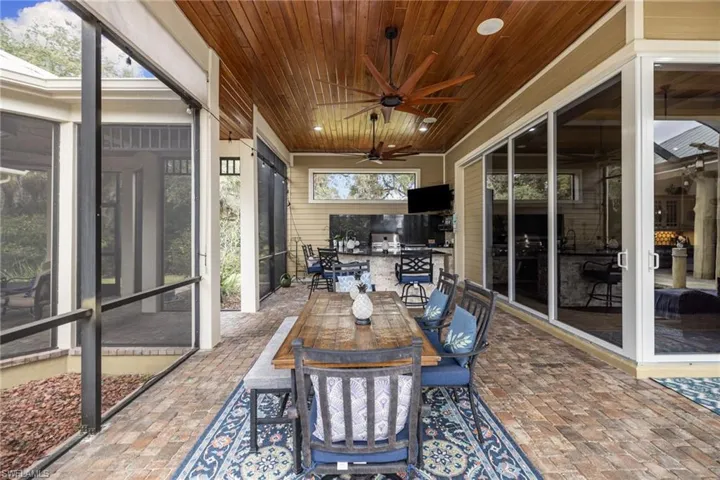 Sunroom / solarium featuring outdoor dining area, a ceiling fan, wooden ceiling, and a patio area