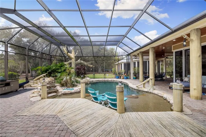 Swimming pool with a sunroom, a patio area, glass enclosure, and outdoor dining area
