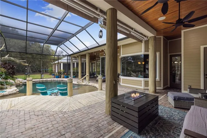 Swimming pool with a patio area, a sunroom, glass enclosure, and an outdoor fire pit