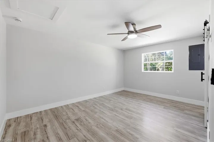 Empty room 2 with electric panel, light wood-style floors, and ceiling fan