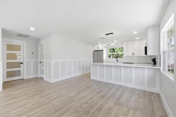 Kitchen featuring pendant lighting, white cabinetry, a peninsula, freestanding refrigerator, and backsplash
