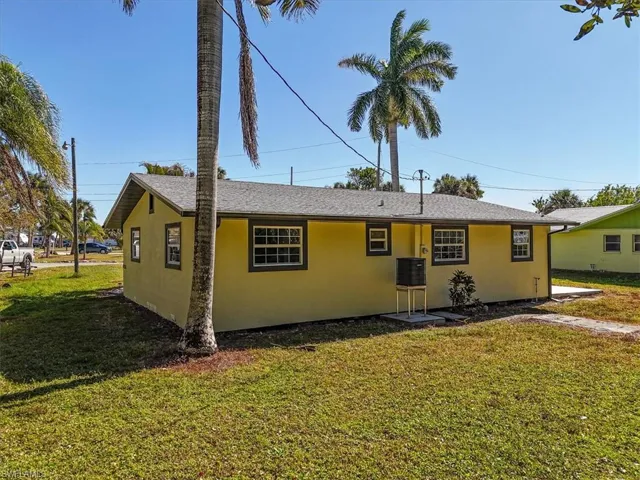 View of back of property with a front lawn, stucco siding, and a shingled roof