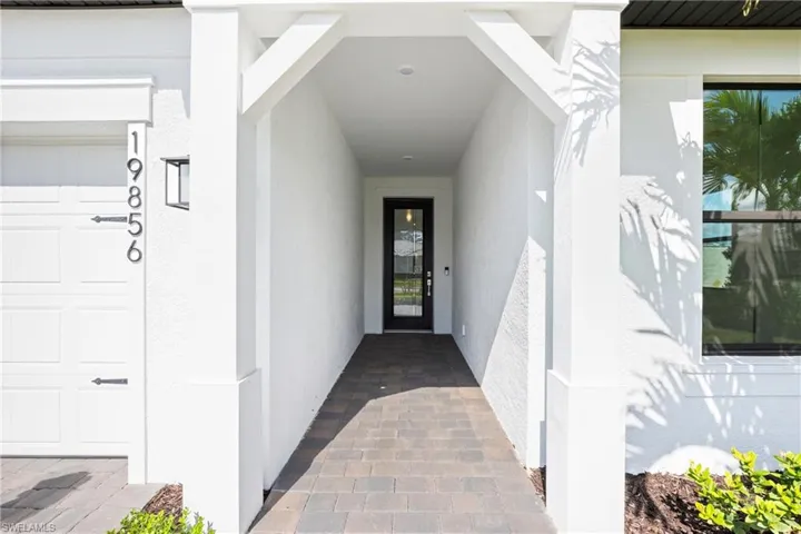 Covered entryway featuring a full-light entry door, paver walkway, and exterior lighting