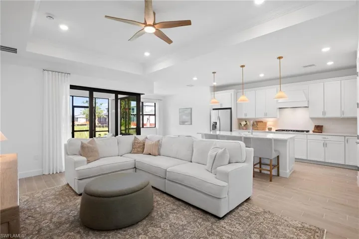 Open concept living space featuring a tray ceiling, recessed lighting, and wood-finish flooring