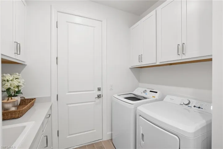 White shaker cabinetry, light-toned countertop, wood-finish flooring, and white paneled door