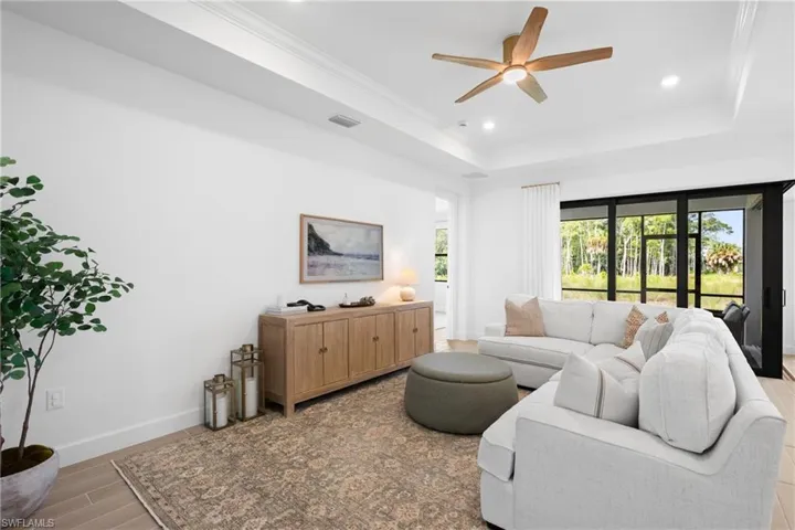 Recessed lighting, ceiling fan with wood-finish blades, tray ceiling, large sliding glass door, and wood-finish flooring