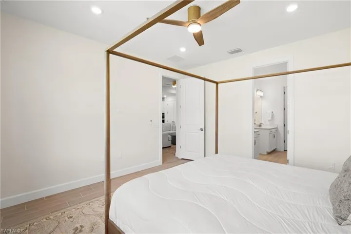 Recessed lighting, wood-finish ceiling fan, wood-finish flooring, white solid core doors, and a bathroom vanity with sconce lighting