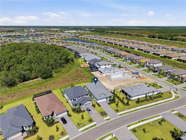 Aerial perspective showcasing the property's location within a developed community, featuring paved roadways, manicured lawns, and surrounding residential structures