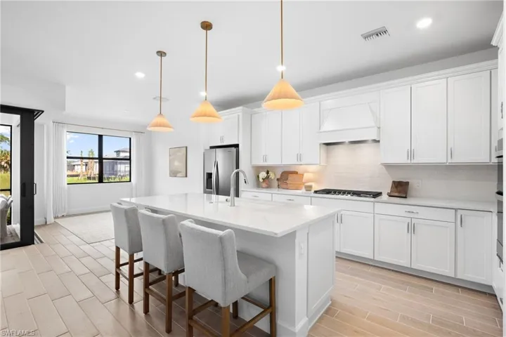Spacious kitchen with white cabinetry, stainless steel appliances, a center island with pendant lighting, and tile flooring
