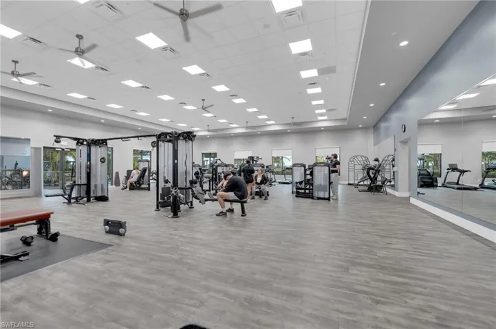 Spacious fitness center featuring modern exercise equipment, wood-finish flooring, and recessed lighting