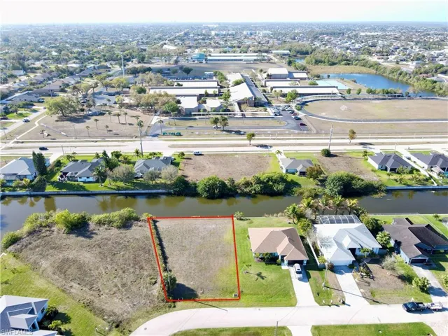 Aerial view of residential area with property parcel outlined and a nearby body of water
