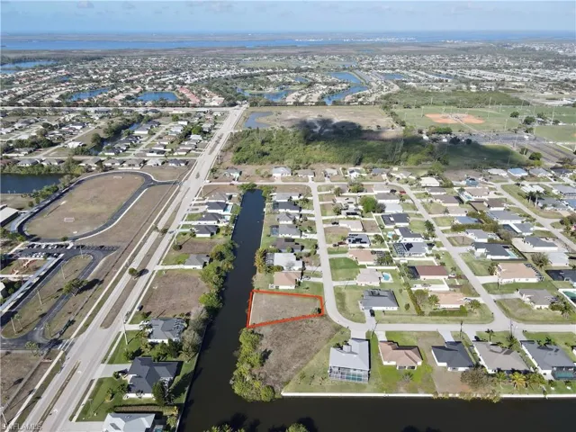 Aerial perspective of suburban area with property boundaries highlighted and a large body of water