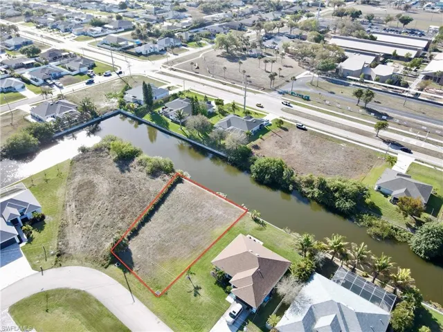 Aerial view of residential area featuring property boundaries highlighted and a nearby body of water
