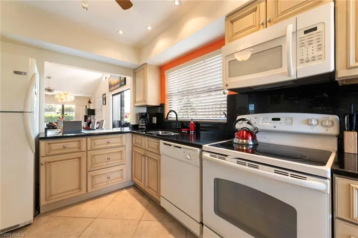 Kitchen featuring white appliances, ceiling fan, light tile patterned floors, a peninsula, and plenty of natural light