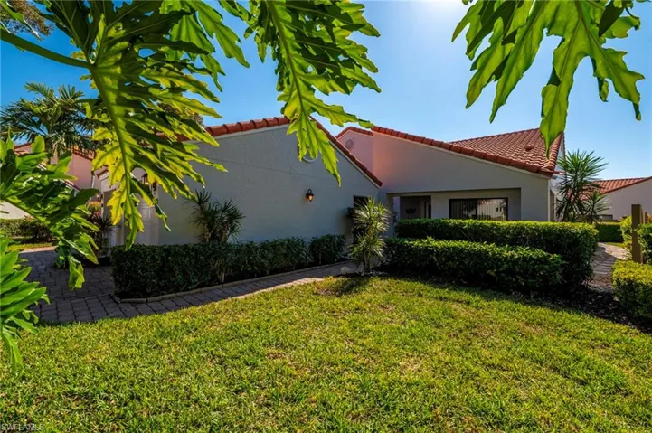 View of side of property with stucco siding, a yard, and a tiled roof