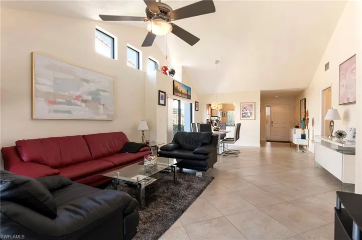 Living room with vaulted ceiling, light tile patterned floors, and ceiling fan