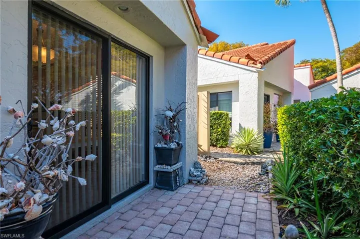 Doorway to property featuring a tiled roof, stucco siding, and a patio area