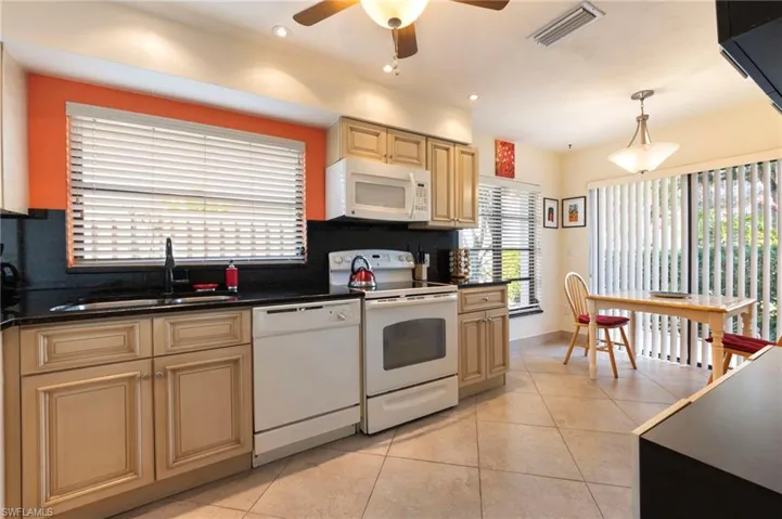 Kitchen featuring white appliances, pendant lighting, a ceiling fan, and backsplash