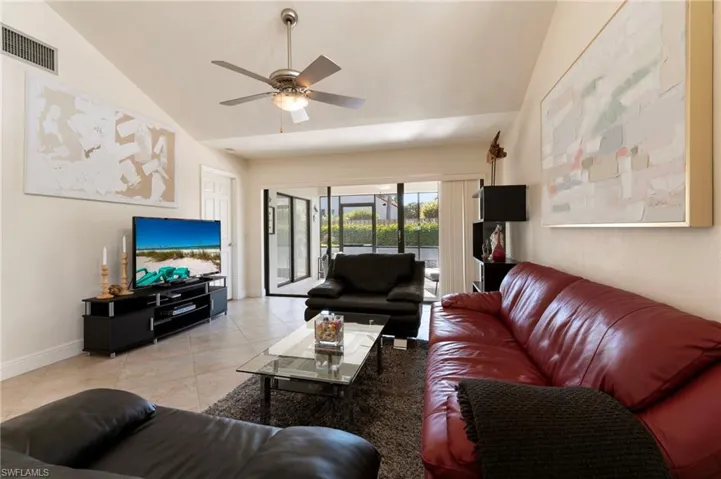 Living area featuring vaulted ceiling, a ceiling fan, and light tile patterned floors