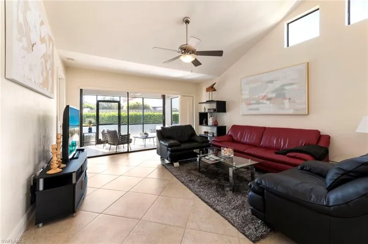 Living area featuring a ceiling fan, light tile patterned floors, and lofted ceiling