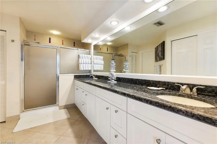 Bathroom featuring a closet, double vanity, recessed lighting, a stall shower, and light tile patterned flooring